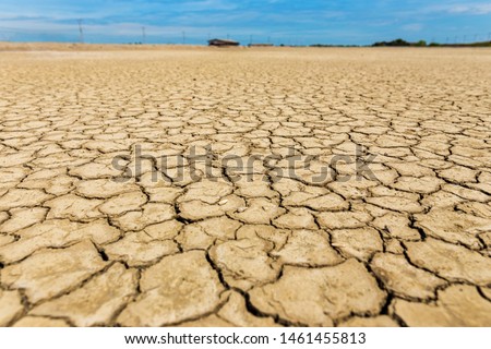 The wide angle of the cracked soil and the fresh blue sky are sparsely white clouds on the sunny days of the dry season, where the water is completely dry due to the El Nino phenomenon causing water s