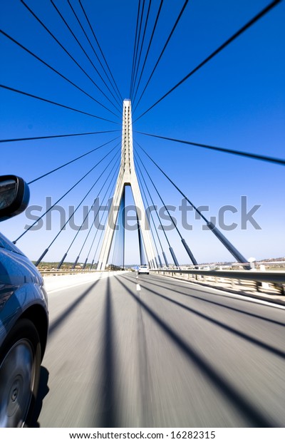 Wide angle driving over a bridge at high speed.\
Focus on bridge tower.