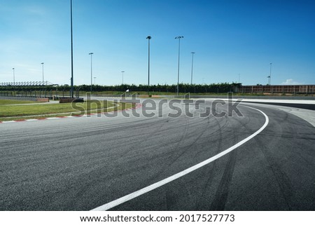 Wide angle empty cornering asphalt modern circuit road and beautiful sunny blue sky background.