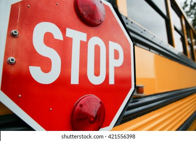  wide angle front view of a bright yellow orange school bus and the big red stop sign  - Powered by Shutterstock