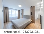 Wide Angle of Home Bedroom Interiom. King Size Double Bed and Wardrobe in Background. White Walls. Family Home. Windows And Curtains. Bright Sunny Day