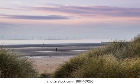 A wide angle image captured through the sand dunes on Crosby Beach of four of the figures which make up Another Place, an installation of one hundred iron figures created by Antony Gormley.