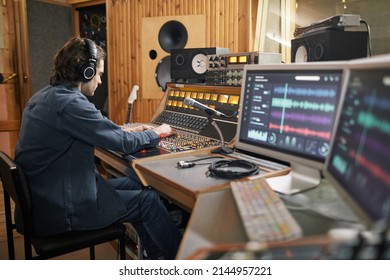 Wide angle at music producer operating audio workstation in professional recording studio, copy space - Powered by Shutterstock