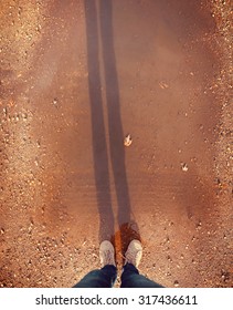  Wide Angle Overhead Shot Of Yellow And White Boat Or Deck Shoes In A Muddy Puddle With A Long Shadow Of The Legs Toned With A Retro Vintage Instagram Filter 