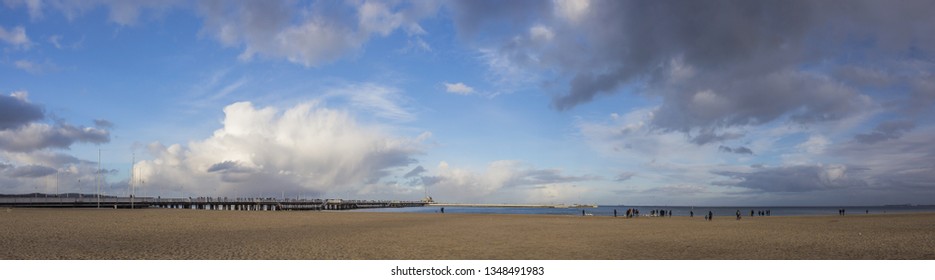 Wide angle panoramic shot of a beach with wooden Pier in Sopot, Poland. Spring cold weather with clouds, dramatic sky.