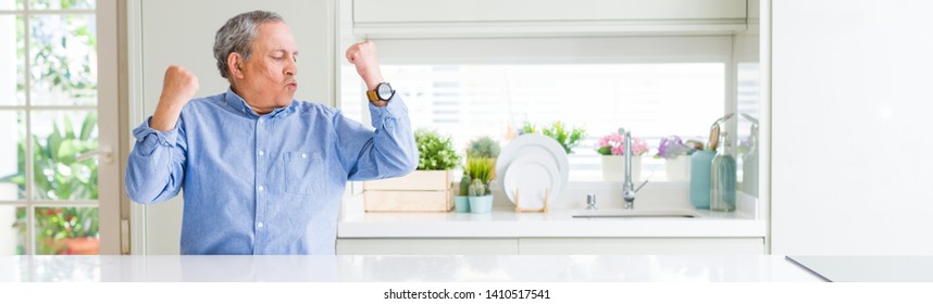 Wide Angle Perspective Of Handsome Senior Man At Home Showing Arms Muscles Smiling Proud. Fitness Concept.