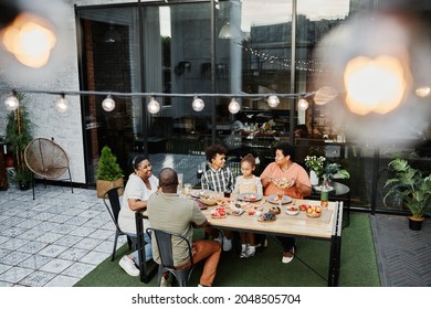 Wide angle portrait of big African-American family sitting at table and enjoying dinner together outdoors, copy space - Powered by Shutterstock