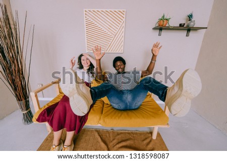 Wide angle portrait of interracial couple make faces, laughing and fooling like children. Happy excited dark skinned young man with white girl expressing funny eccentric emotions. Gestures and grimace