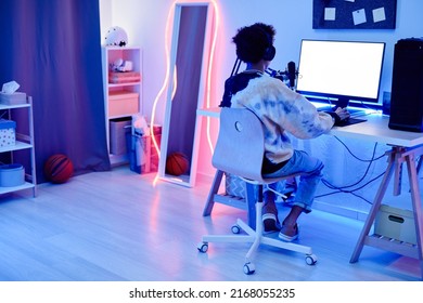 Wide angle angle portrait of teenage boy recording podcast at night in room with blue neon lighting, copy space - Powered by Shutterstock