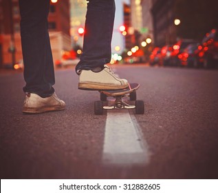 wide angle shot of a guy getting ready to skate down an empty urban street in a dark city toned with a retro vintage instagram filter app or action effect  - Powered by Shutterstock