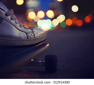 wide angle shot of a guy getting ready to skate down an empty urban street in a dark city toned with a retro vintage instagram filter app or action effect 