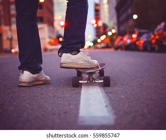 wide angle shot of a guy getting ready to skate down an empty urban street in a dark city toned with a retro vintage instagram filter app or action effect