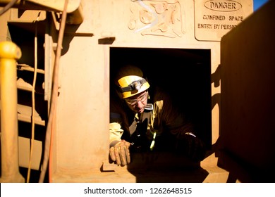 Wide Angle Shot Of Male Rope Access Technician Maintenance Worker Wearing Safety Harness, Helmet Egress Out From Confined Space Restricted Area Entry Door Construction Site, Sydney, Australia  
