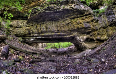 A wide angle shot of a natural rock bridge in a forest.