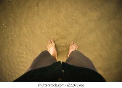 wide angle shot of a pair of feet standing on a sandy beach, feet on the beach. - Powered by Shutterstock
