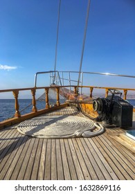 A Wide Angle Shot Of A Rope Twisted In A Circular Position On A Ship Over The Ocean Under A Blue Sky