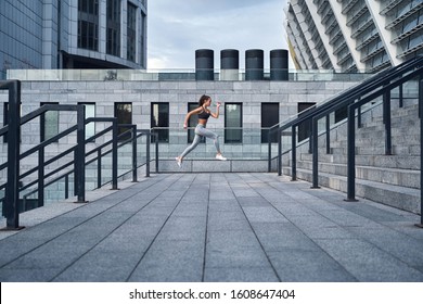 Wide Angle Shot Of Young Athletic Woman Jumping Upstairs, Running Training At Urban City Stadium