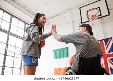 Wide angle shot of young sportsman with disability high five with girl coach during basketball practice in indoor court - Powered by Shutterstock