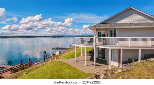 Wide Angle View Of A Beautiful, Large Modern Luxury Summer Holiday Home, Featuring Sun Decks, Glass Railings And Large Windows, Set Beside A Small Lake In Central British Columbia, Canada.