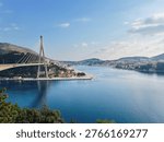 A wide angle view of the cable stayed Franjo Tudman Bridge overlooking the blue waters of the Adriatic Sea and the Port of Gruz in Dubrovnik Croatia.