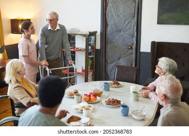 Wide Angle View At Diverse Group Of Senior People Enjoying Breakfast At Dining Table In Nursing Home, Copy Space