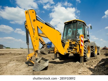 Wide angle view of excavator standing on ground with blue sky and white clouds in background