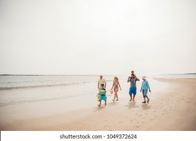 Wide Angle View Of A Family Walking Along The Beach.