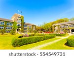 Wide angle view of flags flying over ivy covered main building above grassy quad at Yonsei University on a blue sky day in Sinchon, Seoul, South Korea