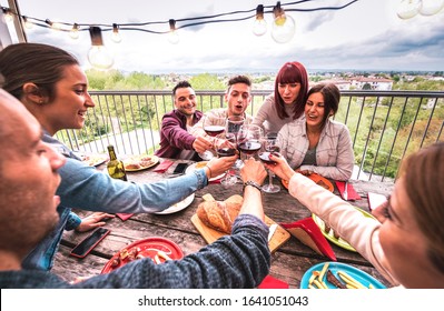 Wide Angle View Of Happy People Toasting Red Wine Together At Rooftop Party In Open Air Villa - Young Friends Eating Bar-b-q Food At Restaurant Patio - Cool Friendship Concept On Warm Vivid Filter