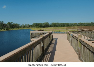 Wide angle view Lake Gwyn Park Wahneta, Florida  looking out on boardwalk on a sunny day with blue sky. Water and grass in bright sun. Green grass and large area of sky. No People. - Powered by Shutterstock