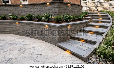 Wide angle view of a multi level stone patio featuring curved retaining walls, integrated garden planters, and illuminated step risers. Warm LED fixtures highlight gray stone masonry in a landscaped backyard setting.