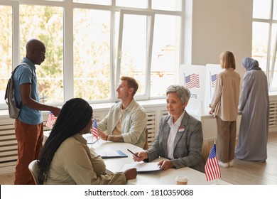 Wide angle view at multi-ethnic group of people voting at polling station decorated with American flags, copy space - Powered by Shutterstock