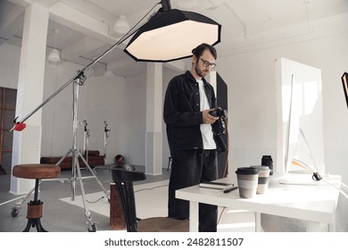 Wide angle view at professional photographer holding camera setting up for photoshoot in white studio interior with big crane light, copy space  - Powered by Shutterstock