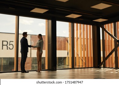 Wide angle view of real estate agent shaking hands with client while standing in empty office building interior lit by sunlight, copy space - Shutterstock ID 1751487947