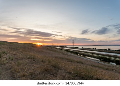 Wide Angle View of Sunset Over Hill With LArge Body of water on the Right