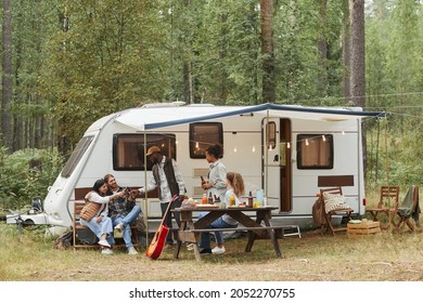 Wide Angle View Of Young People Enjoying Outdoors While Camping With Van In Forest, Copy Space