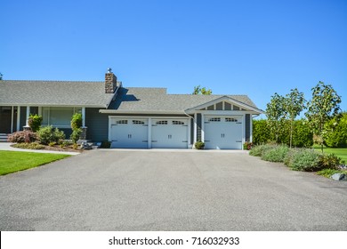 Wide Asphalt Driveway Of Residential House With Three Doors Garage