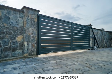 Wide automatic sliding gate with remote control installed in high stone fense wall. Security and protection concept - Shutterstock ID 2177639369