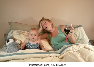 Wide Awake 7 Month Old Baby Girl in Parent's Bed with Tired Frazzled Mother Who Is Drinking A Glass of Wine