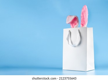 Wide banner on a blue background. The concept of online shopping for Easter, purchases and sale for the holiday. Gift bag with bunny ears