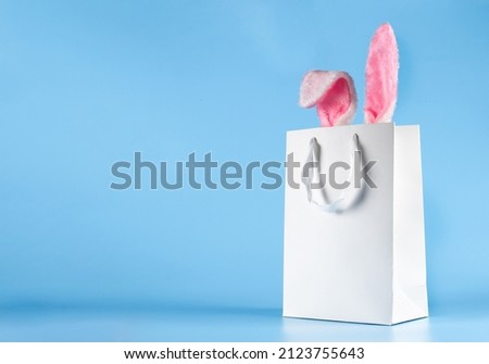 Wide banner on a blue background. The concept of online shopping for Easter, purchases and sale for the holiday. Gift bag with bunny ears