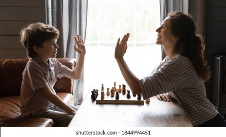 Wide Banner Panorama Image View Of Excited Young Caucasian Mom And Little Son Give High Five After Chess Set. Happy Mother And Small Boy Child Celebrate Win In Board Game. Kid Development Concept.