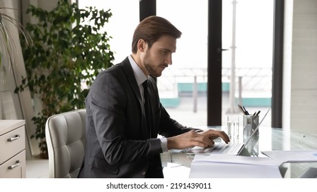 Wide banner panoramic view of focused young Caucasian businessman sit at desk in office work on laptop distant. Serious male CEO look at computer screen consult client or business partner online. - Powered by Shutterstock