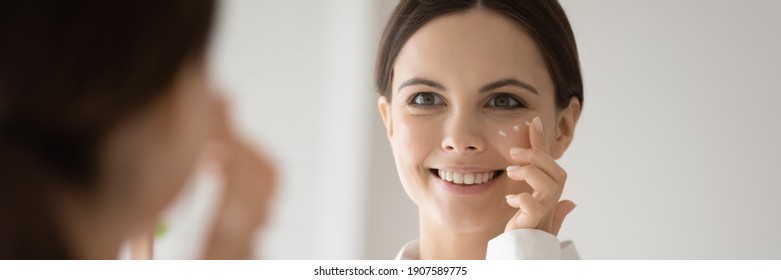 Wide Banner Panoramic View Of Happy Young Caucasian Woman Do Daily Facial Morning Procedures Or Treatment. Smiling Millennial Female Apply Moisturizing Face Cream On Skin. Skincare Concept.