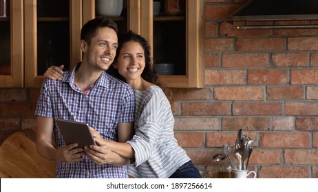 Wide banner panoramic view of smiling millennial Caucasian couple use tablet look in distance dreaming visualizing happy future together. Excited young man and woman user hold browse pad device.