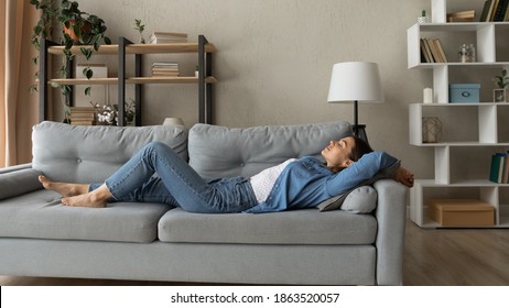 Wide banner panoramic view of young tired Caucasian woman relax lying on comfortable couch in living room. Millennial female rest on sofa at home relieve negative emotions sleep or daydream.