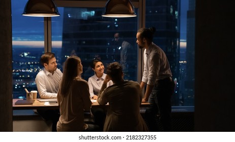Wide banner view or African American male boss or director head meeting with diverse colleagues in office at night. Multiracial employee work late hours, manage to meet deadline. Teamwork concept.