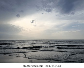 Wide beach landscape with dramatic clouds and abstract water patterns in the sand as a storm approaches the sea. The low tide textures create natural leading lines, while the soft light on the horizon adds a sense of calm before the weather changes. The scene feels contemplative, atmospheric and quietly dramatic.