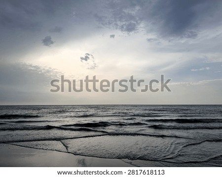 Wide beach landscape with dramatic clouds and abstract water patterns in the sand as a storm approaches the sea. The low tide textures create natural leading lines, while the soft light on the horizon adds a sense of calm before the weather changes. The scene feels contemplative, atmospheric and quietly dramatic.