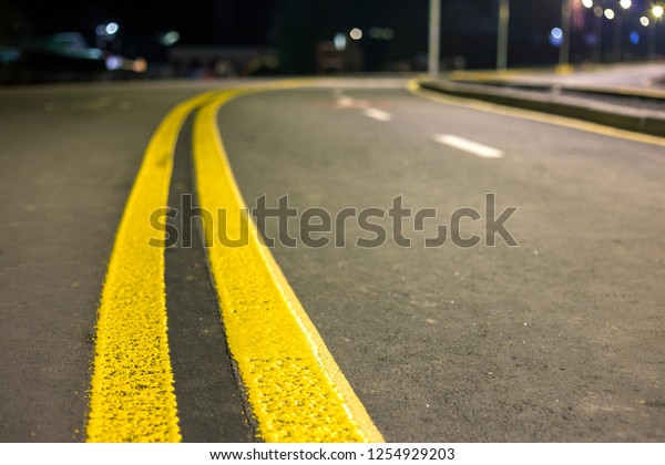 Wide bright yellow street marking sign line\
along modern wide smooth empty asphalt highway stretching to\
horizon. Speed, safety, comfortable journey and professional road\
building concept.
